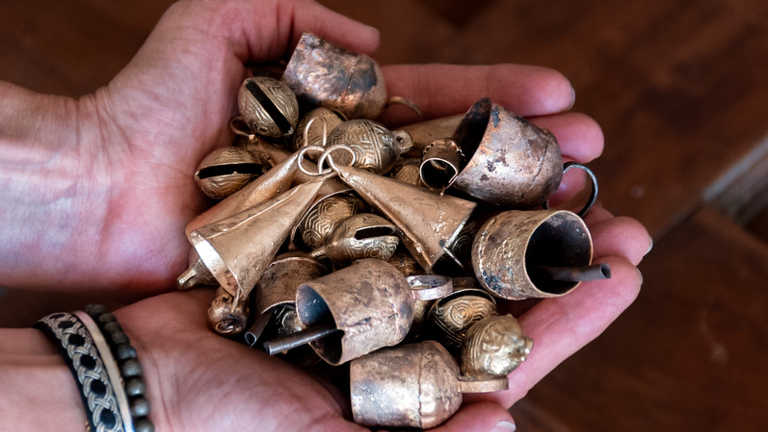 Hands holding an assortment of antique golden bells.