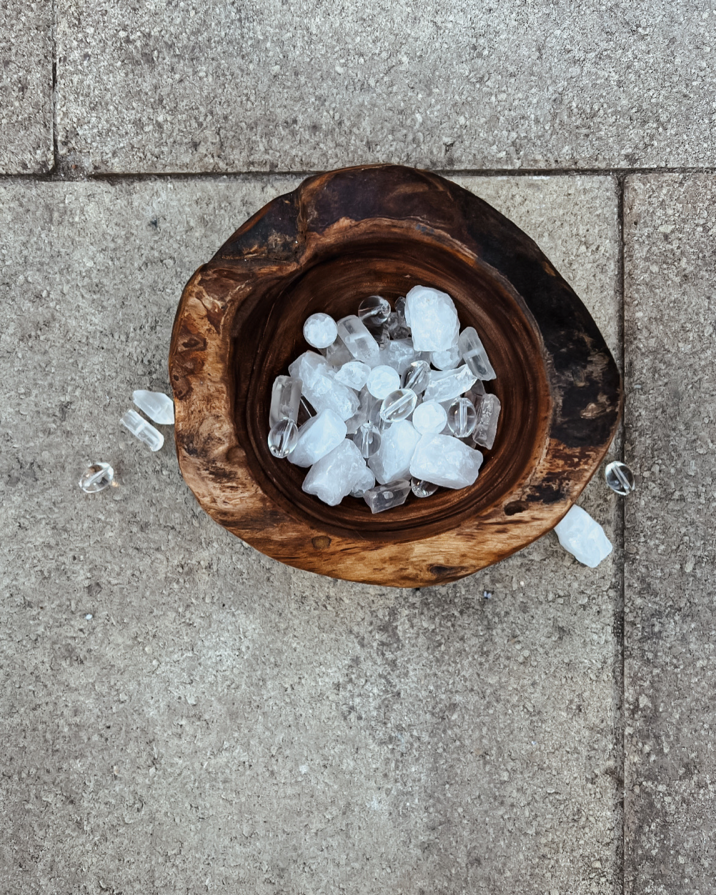 Photo of an overhead view of a wooden bowl full of clear quartz crystals.