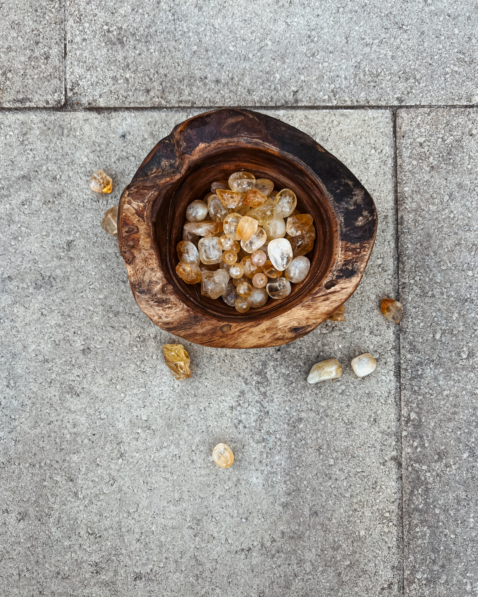Photo of overhead view of a wooden bowl full of citrine crystals.