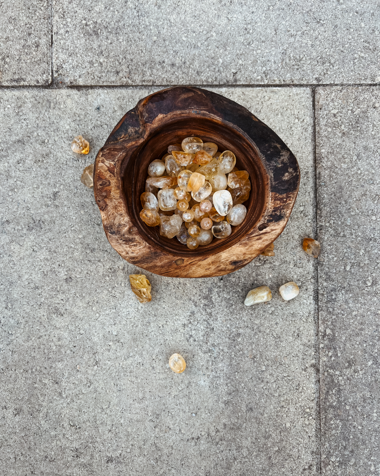 An overhead photo of a wooden bowl full of citrine crystals.