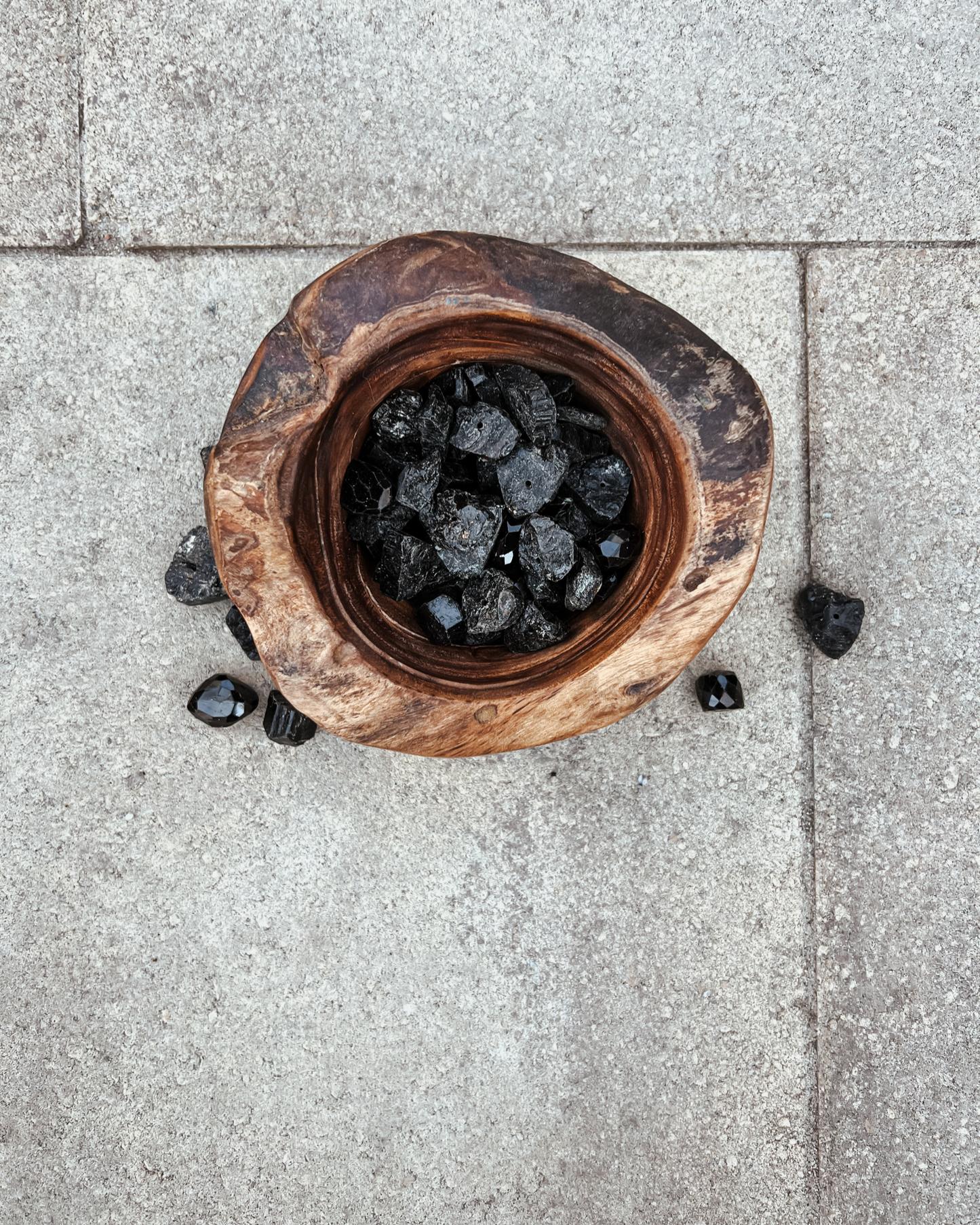 Photo of an overhead view of a wooden bowl full of black tourmaline crystals.