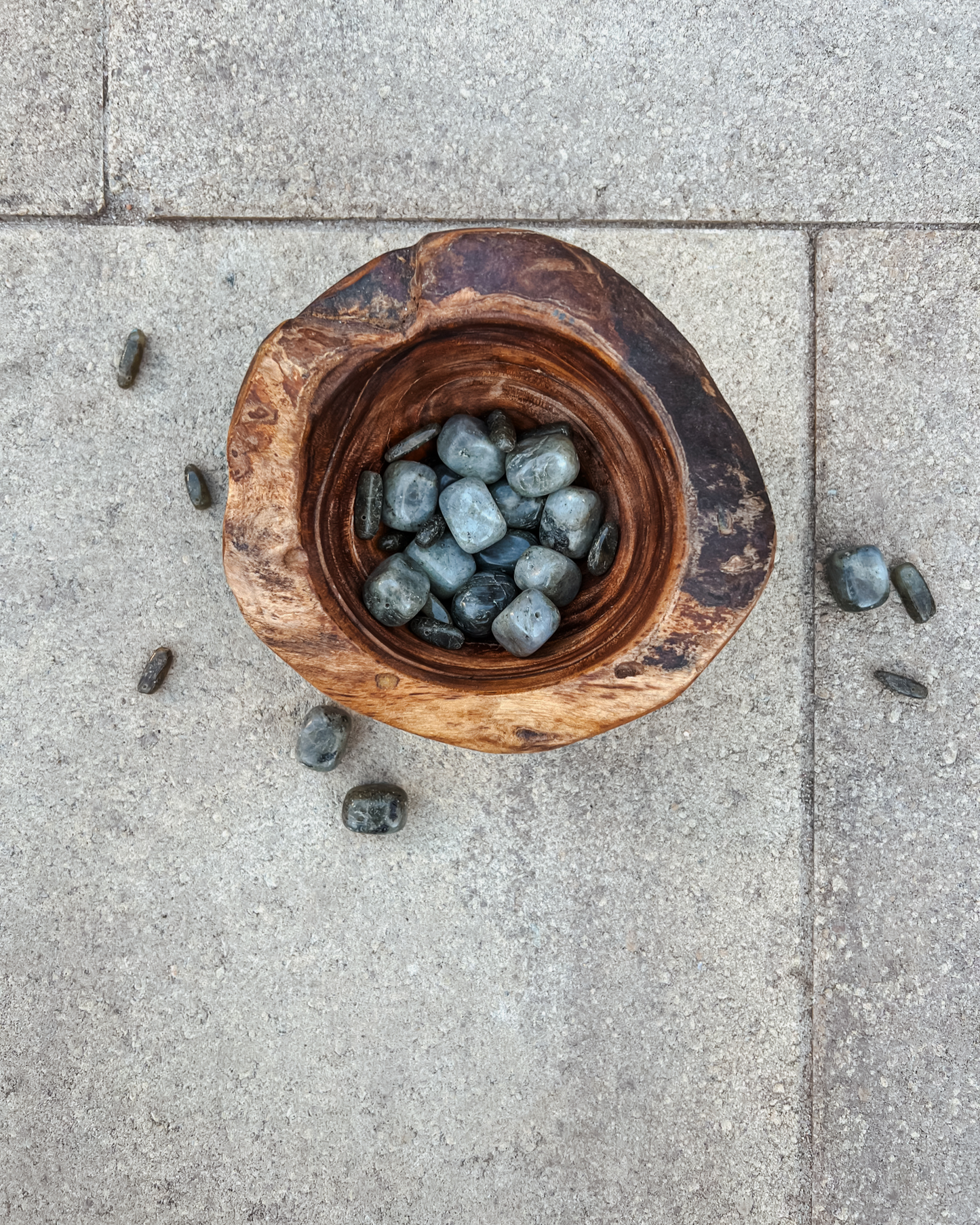 Product image of an overhead view of a wooden bowl full of labradorite crystals.