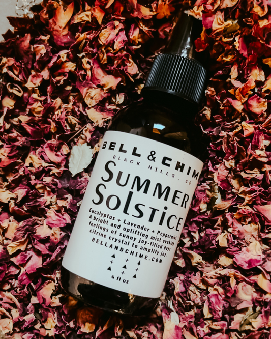 Bell & Chime "Summer Solstice" clearing mist laying in a bed of dried rose petals.