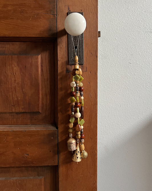 Triple strands of wooden bells, serpentine crystals,  and three golden bells hanging from an antique doorknob
