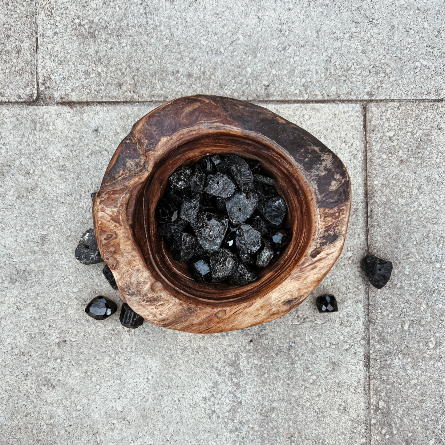 Photo of an overhead view of a wooden bowl full of black tourmaline crystals.
